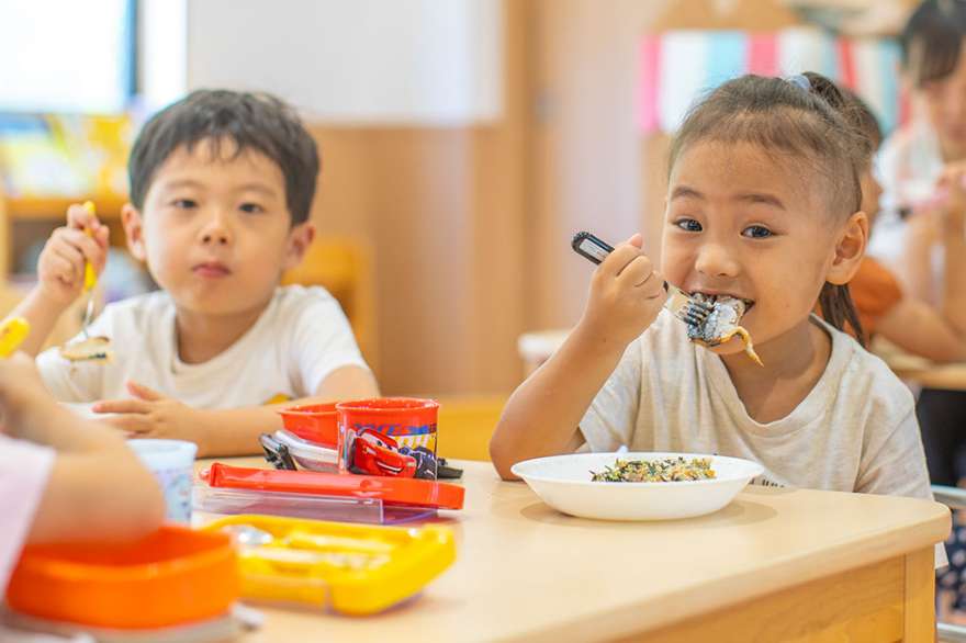 園児達がフォークフォ使って昼食を食べている写真