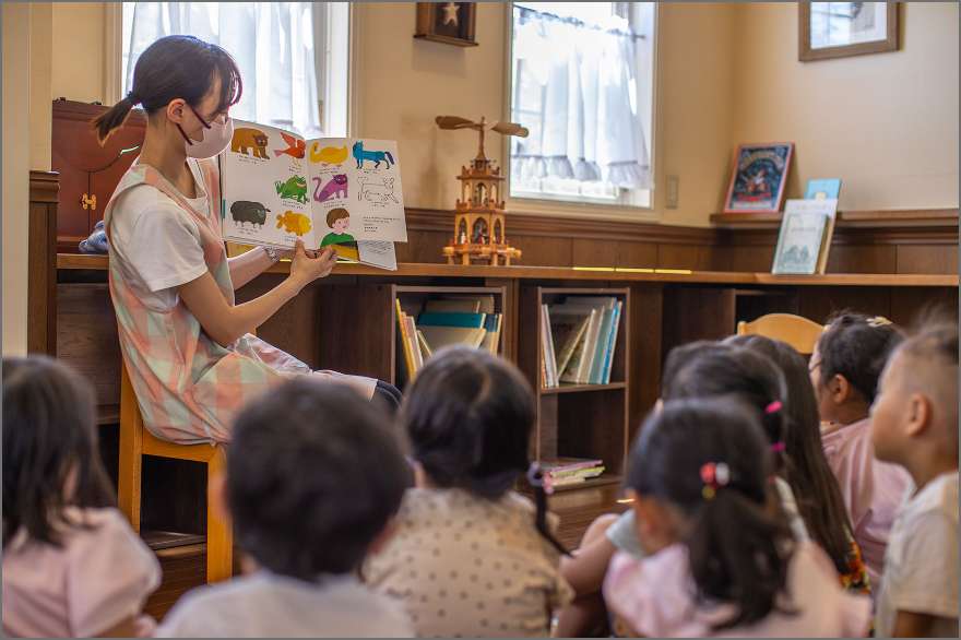 先生が子供達に絵本の読み聞かせをしている写真