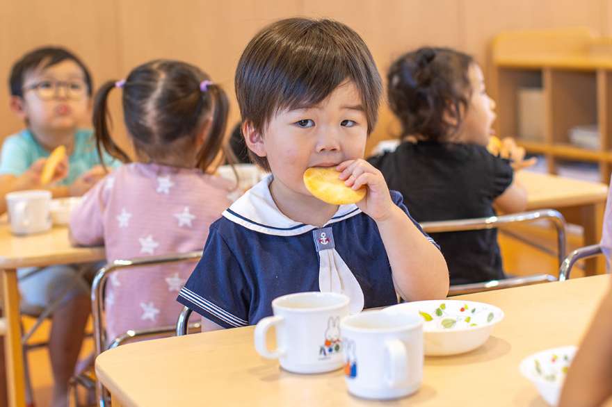 園児達が手でおやつを食べている写真